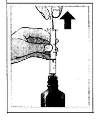 A hand holding a syringe with needle inserted into a vial while another