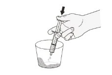 Una mano impugna una siringa verticalmente per aspirare il contenuto da un bicchiere contenente un liquido con una freccia nera in alto