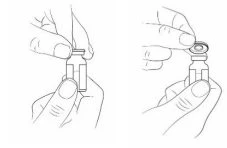 Disegno tecnico che mostra due mani che impugnano un piccolo flaconcino di vetro per rimuovere il tappo di protezione superiore