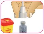 A hand holds a white vial above a yellow sharps container and a small gray glass vial