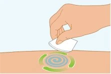 Una mano applica un cerotto bianco su una zona della pelle contrassegnata da un simbolo circolare blu e verde a spirale