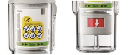 Two views of a transparent medical device with a yellow label featuring checkmarks and a red arrow pointing downward on a white background
