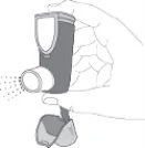 A hand holding a medical inhaler while a spray cloud is being emitted from