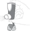 Una mano tiene un inalatore a polvere che emette una nuvola di particelle attraverso l