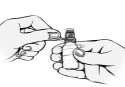 Two hands handling a small glass vial to prepare the medication with a
