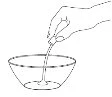 Una mano tiene una boccetta e versa il contenuto liquido all'interno di una ciotola trasparente con un flusso sottile e continuo