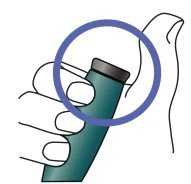 Una mano impugna un dispositivo medico cilindrico verde con un cappuccio grigio evidenziato da un cerchio blu superiore