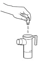 Una mano tiene un flacone capovolto per far cadere delle gocce di liquido all'interno di un contenitore cilindrico con beccuccio e manico