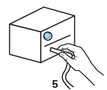 Una mano impugna un dispositivo a forma di penna per inserirlo in una fessura orizzontale su un contenitore cubico con un piccolo cerchio blu
