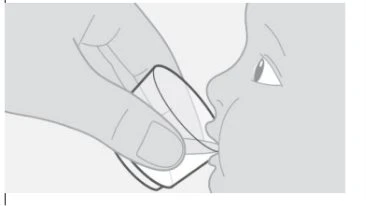 Una mano tiene un piccolo bicchiere di plastica vicino alle labbra di un bambino per somministrargli un liquido