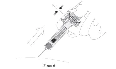 A hand holding a syringe with the needle pointing upward