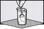 Una mano tiene un cucchiaio all'interno di un bicchiere pieno di liquido poggiato su una superficie piana