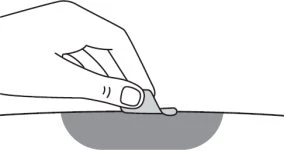 Una mano tiene un piccolo oggetto piatto e grigio appoggiandolo su una superficie curva e scura che rappresenta una parte del corpo