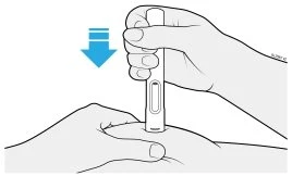 A hand holding a white medical device and pressing it downward against the skin of a