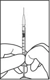 Two hands hold vertically a syringe with a thin needle and graduated barrel for preparing a