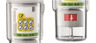 Two transparent medical devices with yellow and green labels and a white arrow on a red background indicating the direction of use