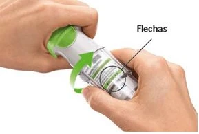 Two hands holding and rotating a cylindrical medical device with green arrows indicating the rotation direction toward the