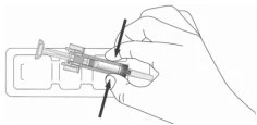 Una mano impugna una siringa con due frecce nere che indicano la pressione necessaria sui lati del corpo del dispositivo per l'uso