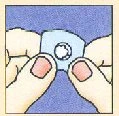 Two hands holding and lifting a small blue adhesive patch with a central white disk against a blue background