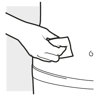 Una mano stringe un piccolo oggetto rettangolare bianco sopra una superficie curva chiara con il numero 6 accanto