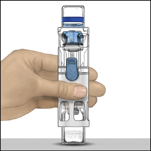 Una mano sostiene verticalmente un dispositivo médico transparente con componentes azules y una parte inferior que contiene líquido