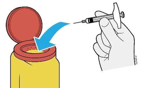 A hand holds a syringe with needle pointing toward the