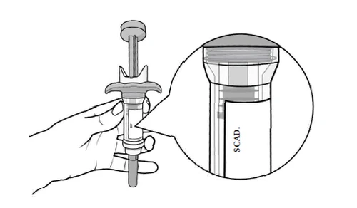 A hand holding a cylindrical medical device with an inset showing a close-up of the label 'SCAD' on the container body