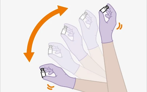Gloved hands holding a medical vial performing a rotational movement indicated by a curved orange arrow on a white background