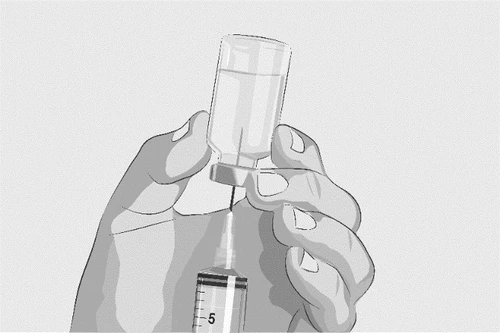 Two hands hold a glass vial while a needle inserted through the cap draws liquid into a graduated syringe positioned below it