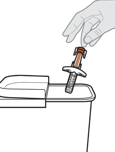 A hand holds a medical device with an orange cylinder and inserts it vertically into a white medical waste disposal container