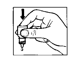A hand holding a bottle tilted downward while a drop of liquid falls from the tip