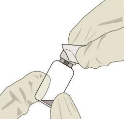 Two gloved hands holding a white glass vial with a gray cap to prepare the medication