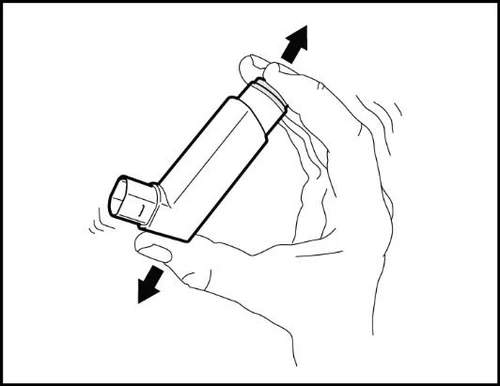 Una mano tiene un inalatore con le dita che premono la parte superiore e inferiore per rilasciare il farmaco indicato dalle frecce nere