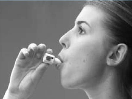 Profile of a woman holding a small white box near her open lips to take the medication, in black and white