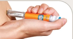 Una mano tiene una penna iniettore arancione e bianca mentre l'ago viene inserito nella parte superiore del braccio di una persona