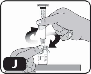 A hand holding a syringe and rotating it clockwise to insert the