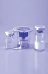 Three transparent glass vials with white metal caps arranged on a light surface with a monochromatic lilac background