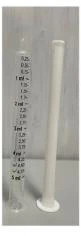 Jeringa graduada transparente con marcas milimétricas de 0,25 a 5 ml junto a una tapa protectora cilíndrica blanca sobre fondo gris
