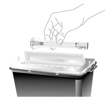 A hand holding a white injection pen with red and green details above a black and white medical waste disposal container