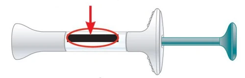 Cylindrical white medical device with a central black indicator highlighted by a red circle and a red arrow pointing downward