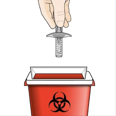 Una mano sostiene una jeringa usada sobre un recipiente rojo para residuos biológicos con el símbolo de riesgo biológico negro