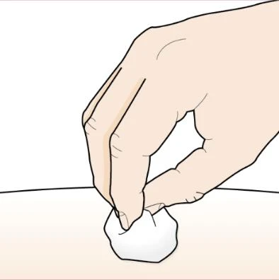A hand holding a white cotton ball and gently pressing it onto a light skin surface