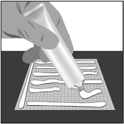 Una mano schiaccia un tubetto di crema per applicare strisce orizzontali di prodotto bianco su una superficie a griglia quadrata