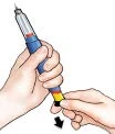 Una mano impugna una penna iniettiva blu e argento mentre l'altra mano ruota la base gialla verso il basso indicata da una freccia nera