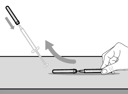 A hand holds a syringe on a flat surface while a
