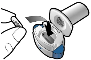 A hand holding a test strip above an open medical device with an internal compartment and a white and blue top