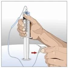 A hand holding a syringe with an attached tube while another