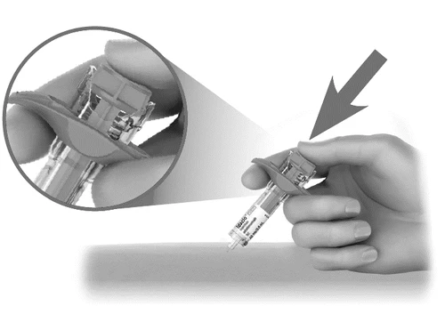 A hand holding a syringe-like medical device with a circular magnification showing the detail of the upper part of the device