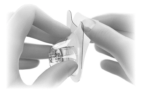 Two hands gently holding and separating a transparent medical device with a circular base and a thin flexible membrane