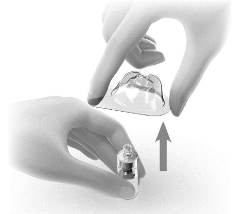 Two hands lifting a transparent cap to place it over a small cylindrical glass vial on a white surface